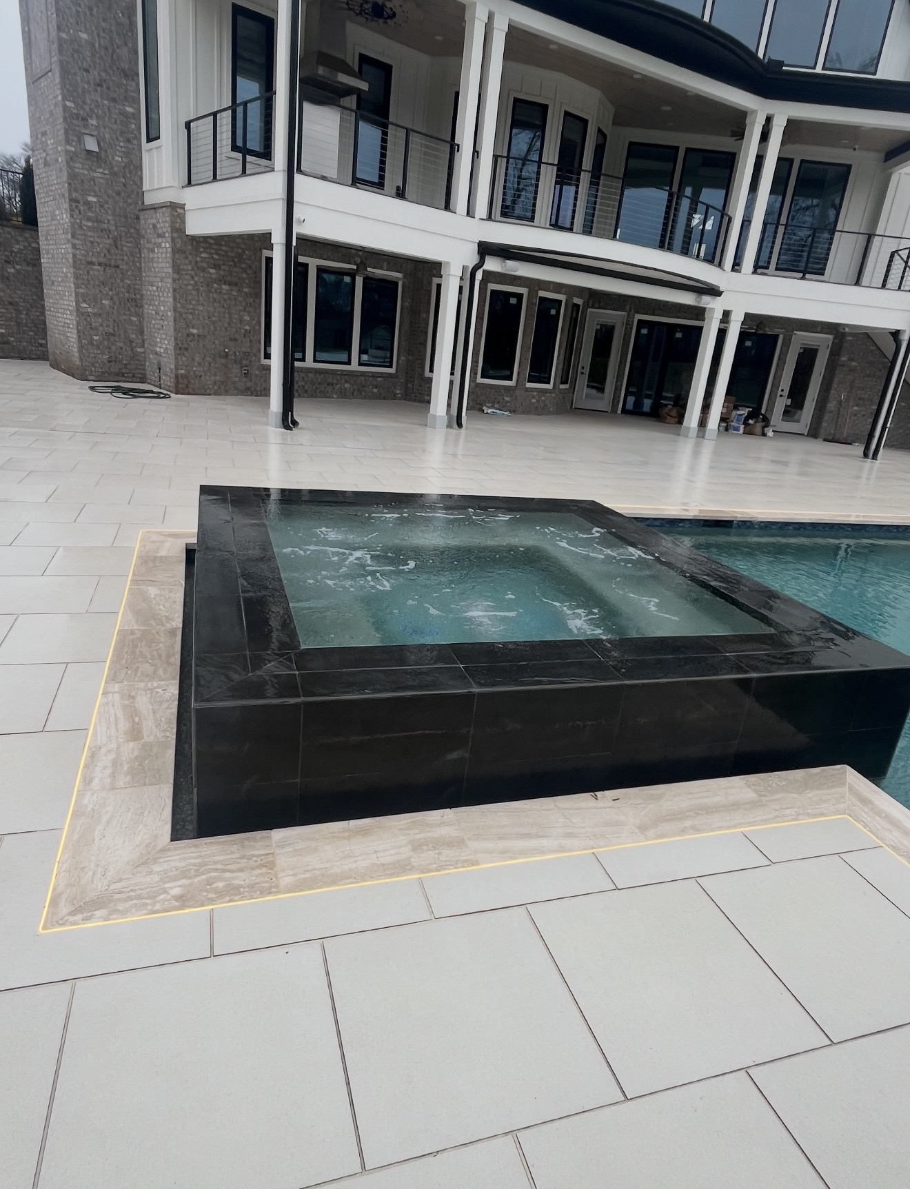 Modern black tile spa with sun shelf and porcelain paver deck