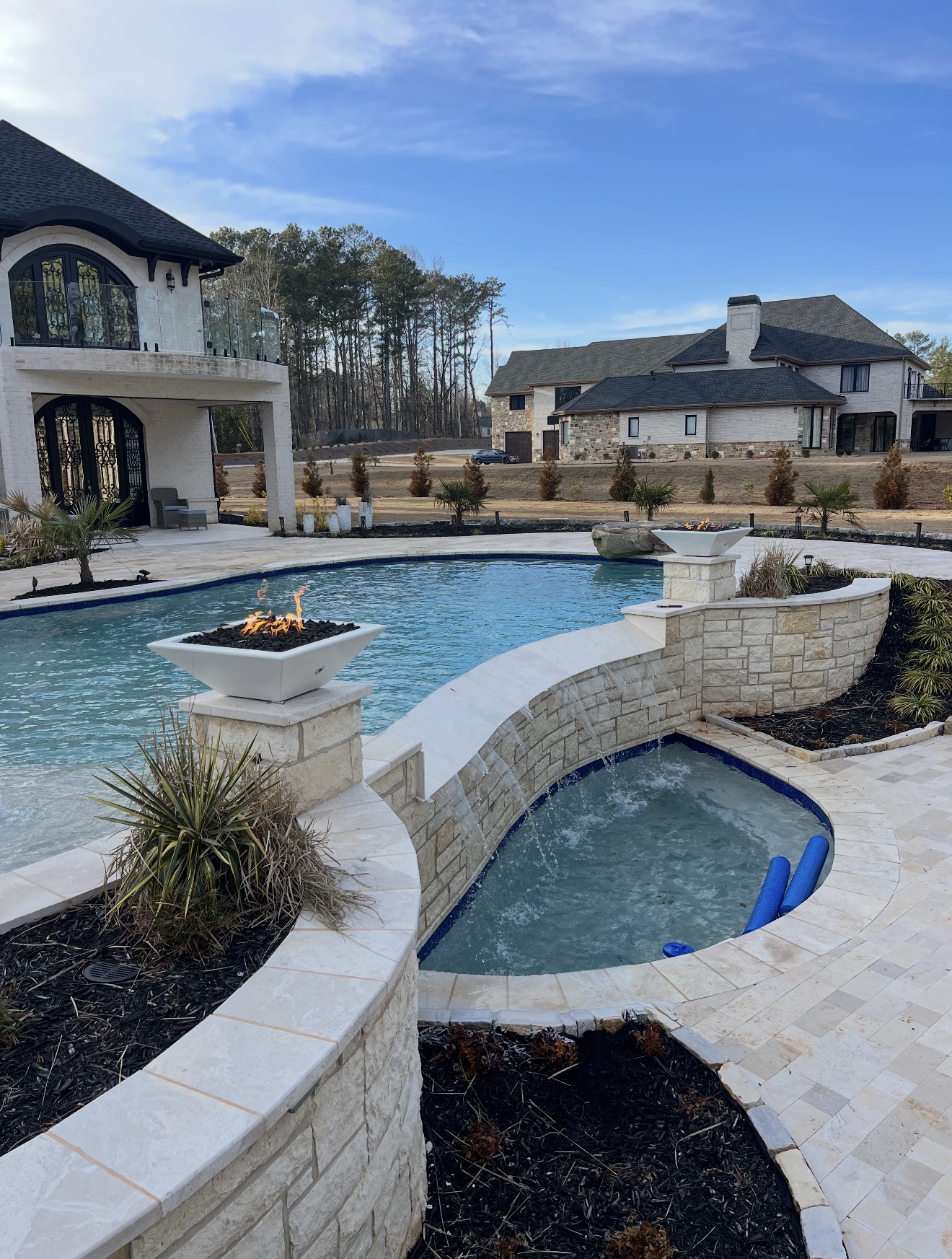 Freeform luxury pool with spa and lit fire bowls