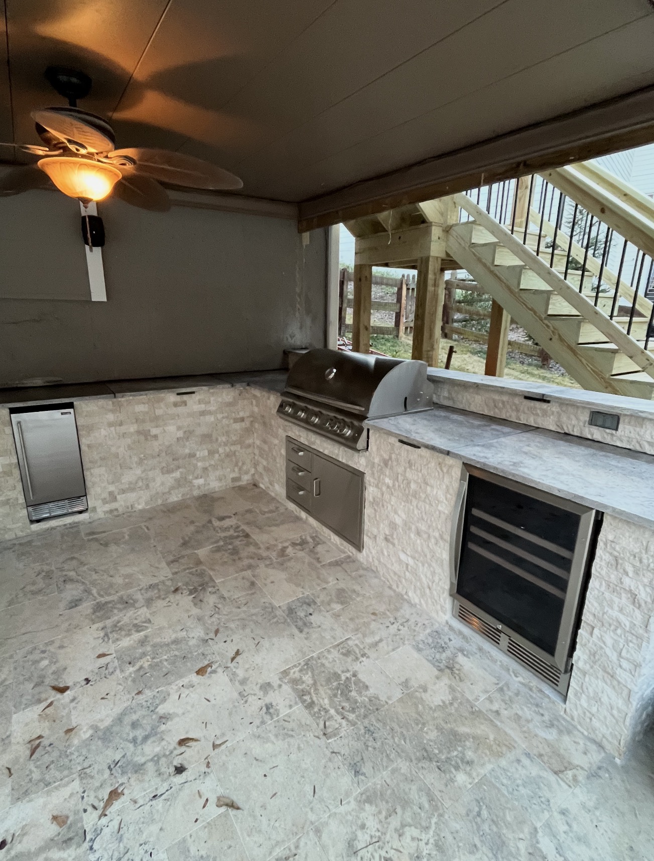 Stone outdoor kitchen with grill, wine fridge and ice maker