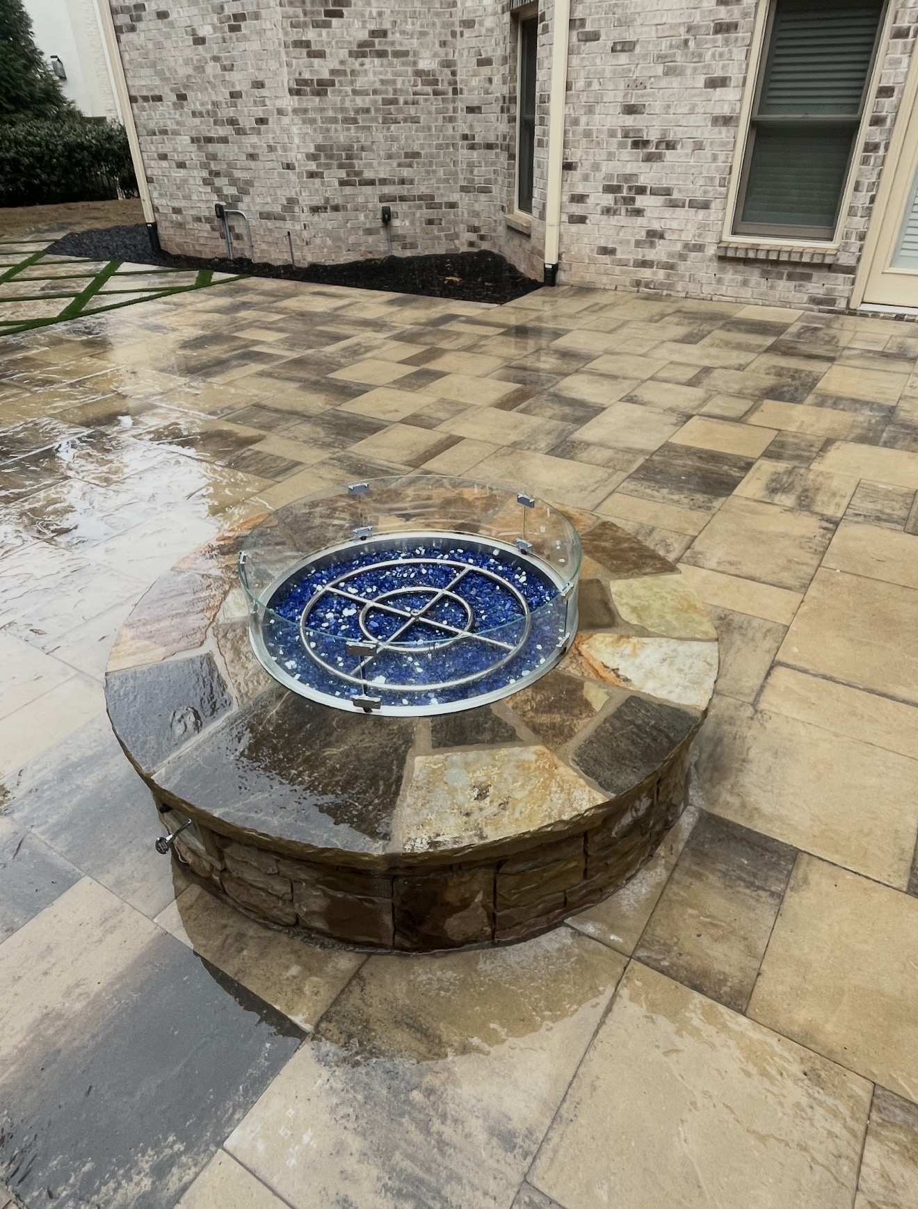 Round stone gas fire pit with blue fire glass